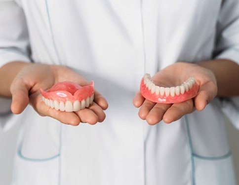 Dental team member holding upper and lower dentures