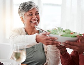 Smiling woman grabbing bowl of salad