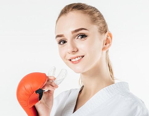 Teen girl in boxing gloves holding athletic mouthguard