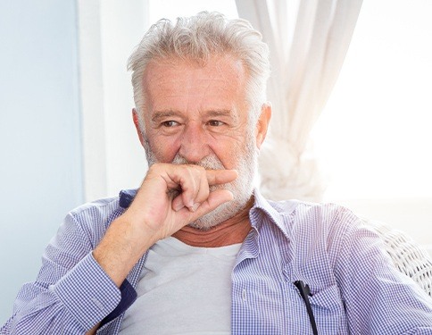 Older man in need of dental crown covering his smile