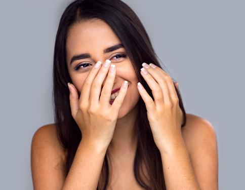 Woman in need of dental crown hiding smile