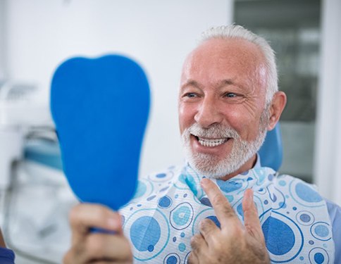 senior man admiring his new smile with dental implants in Tyler