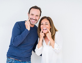 man and woman pointing to their smiles 