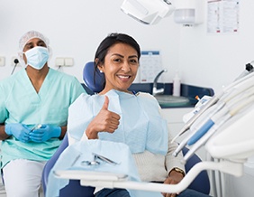 Woman giving thumbs up after dental implant surgery