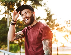 Young man with red shirt and tattoos smiling