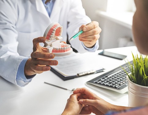 Dentist pointing to model of teeth in office