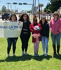 Team members and community members with a make a wish sign