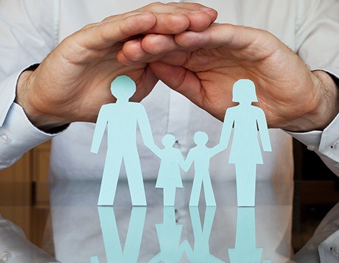 Hands covering paper cut out family