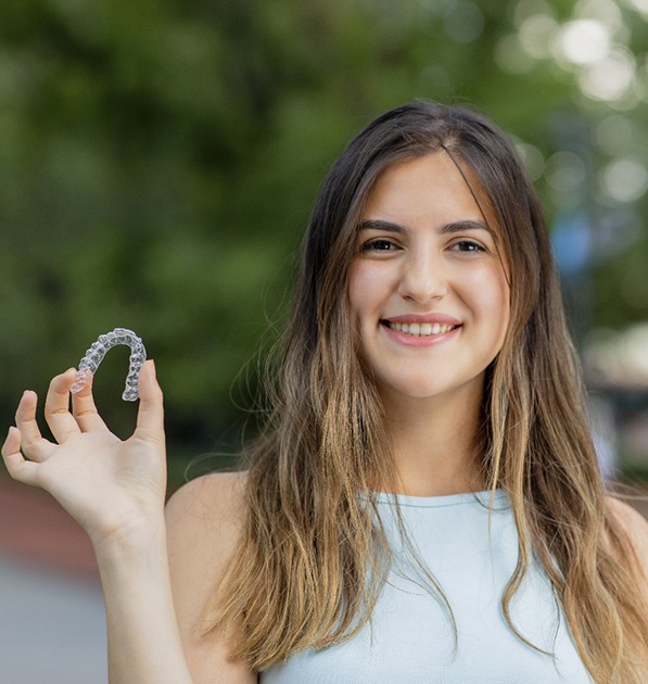Smiling woman holds Invisalign in Tyler