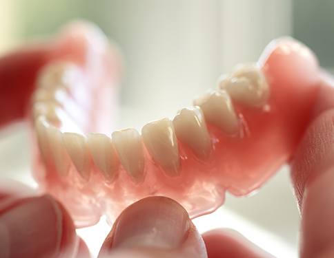 Hand holding a full denture