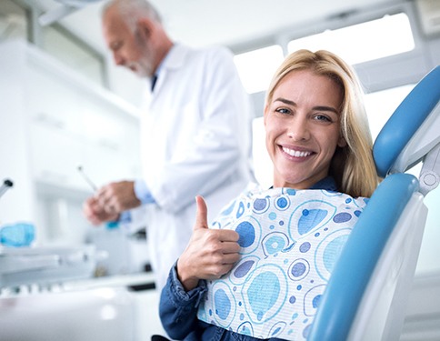 Woman giving thumbs up at end of dental appointment