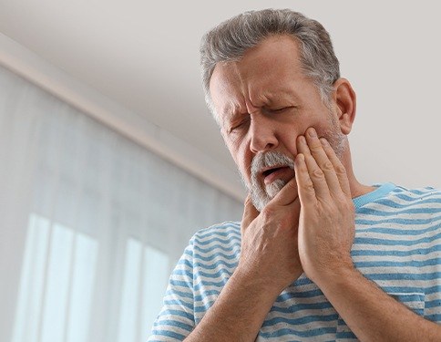 Man in need of root canal holding cheek