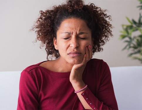 Woman in need of root canal holding cheek