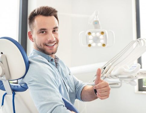 smiling man giving thumbs up in dental chair 