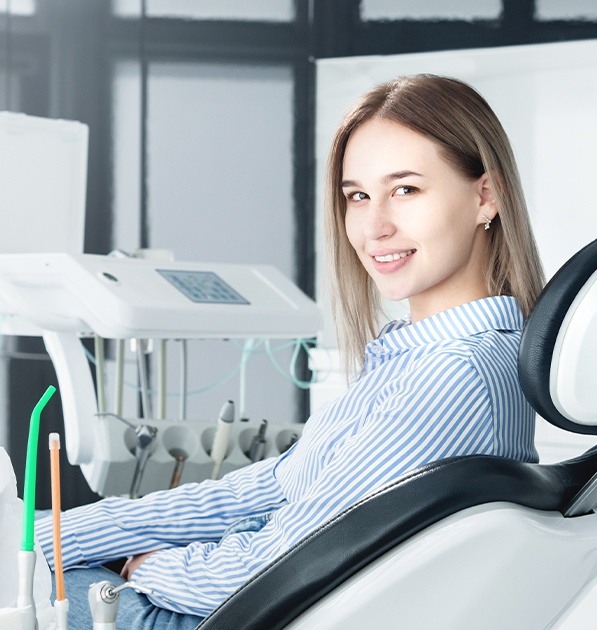 Woman in dental chair smiling after modern dental exam