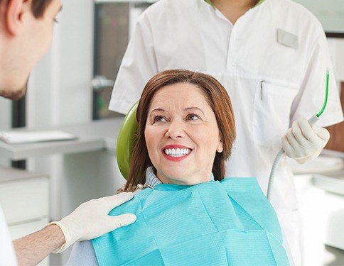 Older woman in dental chair smiling at dentist