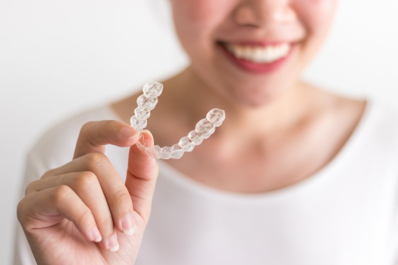 an up-close view of a person holding an Invisalign aligner after wearing braces