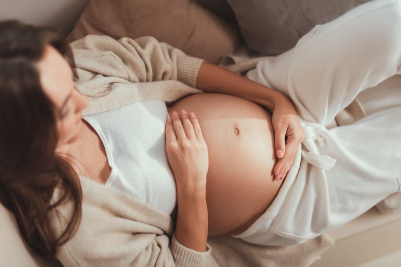 Pregnant woman lying down and looking at her belly