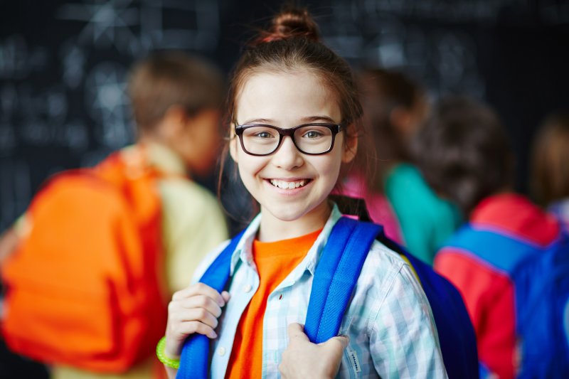 Closeup of girl with backpack and glasses smiling