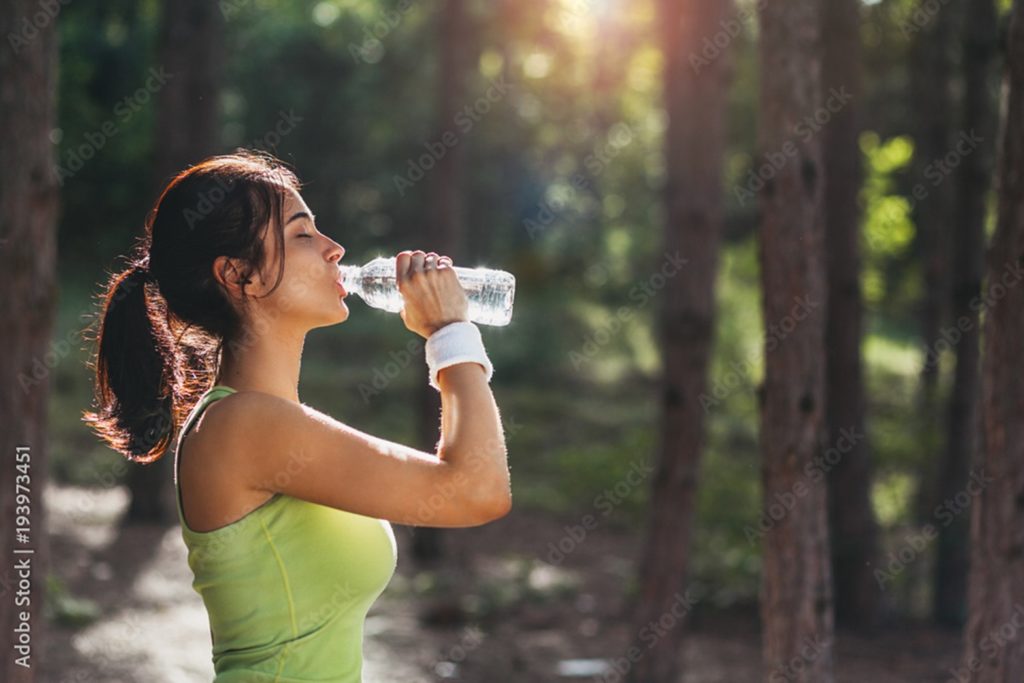 Woman drinking from a water bottle during summer.