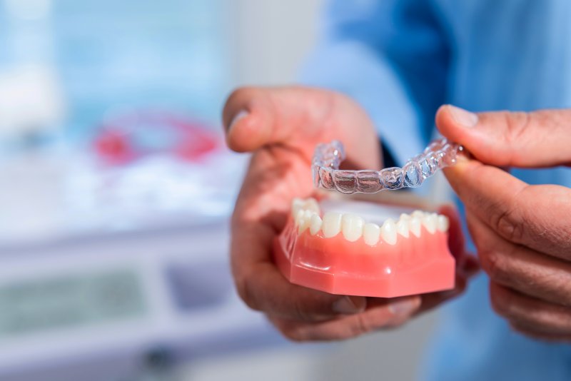 dentist putting an aligner on a model of your teeth